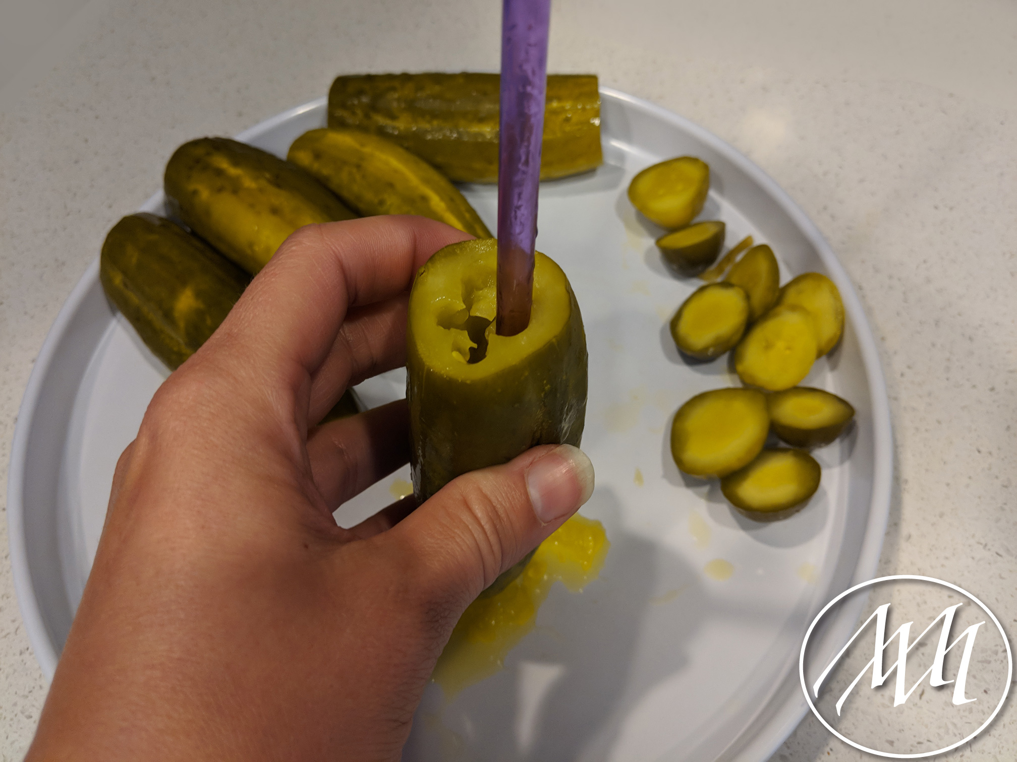 Using a plastic straw to core out the pickles